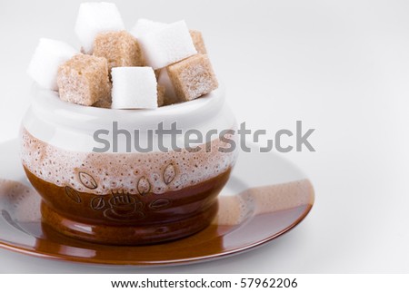 Cubes of beet and cane sugar in sugar-basin on gray background