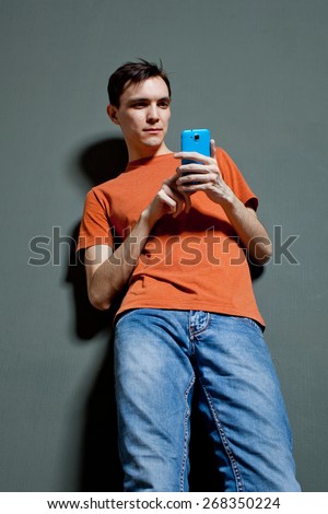 guy with the phone dials sms standing against the wall