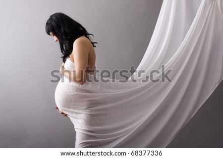 pregnant girl covered with cloth looks down in front of him