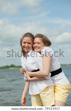 twins girls hugging and laughing with one best man on the shore
