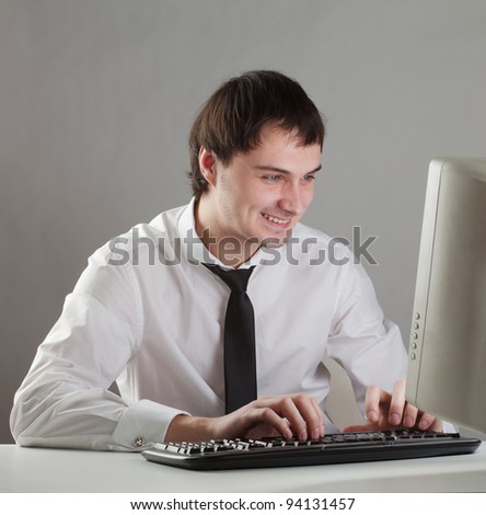 young man at the computer happy, looking at the monitor