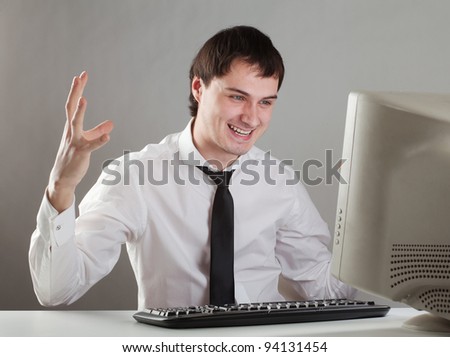 young man at the computer enjoys raising his hands