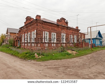 Old brick mansion with palisade and road before against cloudy sky background. Gorodets, Nizhegorodsky region, Russia.
