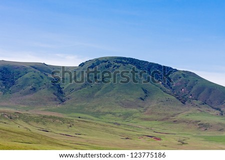 View mountain slope in savanna with meadow against blue sky background. Serengeti National Park, Tanzania, Africa.