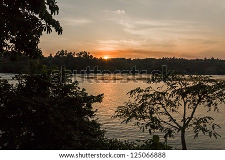Victoria Nile River at sunset with bright Sun reflecting in water against evening glow background. Jinja, Uganda, Eastern Africa.