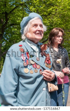 MOSCOW/RUSSIA - MAY 9: Old woman veteran of WWII in blue coat decorated with numerous orders and medals during festivities devoted to anniversary of Victory Day on May 9, 2011 in Moscow.