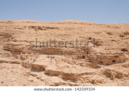 Kidron river strata canyon panorama with monastic cave-cells in the mountain wall viewed from terrace of The Great Lavra of St. Sabbas the Sanctified (Mar Saba) in Judean desert. Palestine, Israel.