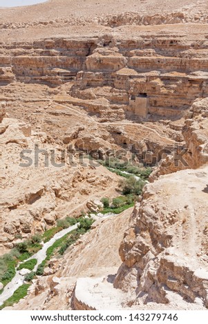 Kidron river strata canyon panorama with monastic cave-cells in the mountain wall viewed from terrace of The Great Lavra of St. Sabbas the Sanctified (Mar Saba) in Judean desert. Palestine, Israel.