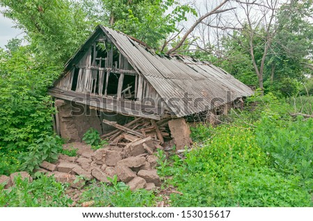 Old disturbed dry dung barn among wild tall weeds. Bolshaya Doroga village, Tambovsky region, Russia.