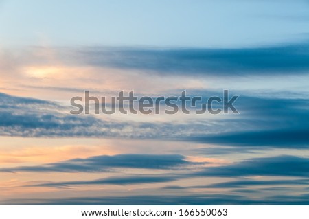 Oblong clouds against evening glow background at sunset