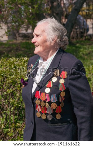 MOSCOW/RUSSIA - MAY 9: Old woman veteran of WWII in black coat decorated with numerous orders and medals stands in Gorky Park during festivities devoted to Victory Day on May 9, 2013 in Moscow.