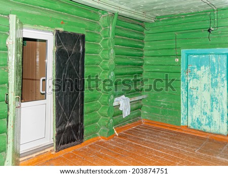 Log cabin hallway interior with green walls, rown floor and white plastic door.