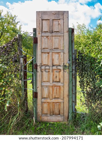 High wooden door in garden fence with barbed wire. Nikolo-Uryupino village, Moscow region, Russia.