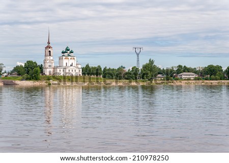 View on Vychegda River with ancient Annunciation Cathedral on riverside reflecting in water against cludy sky background. Solvychegodsk, Arkhangelsky region, Russia.