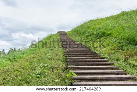 Long wood stairs to top of grass-covered earth-deposit. Belozersk, Vologodsky region, Russia.