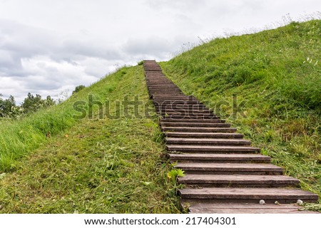 Long wood stairs to top of grass-covered earth-deposit. Belozersk, Vologodsky region, Russia.