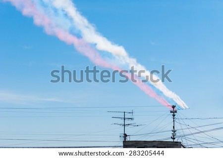 Color smokes in the form of Russian flag (tricolor) made by jet aircrafts against blue sky background.
