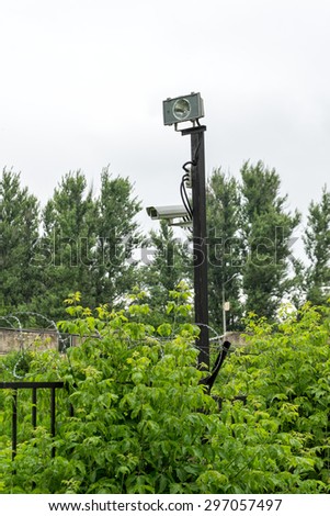 Camera with motion sensor and lamp on restricted fence of controlled area with barbed wire. Moscow, Russia,