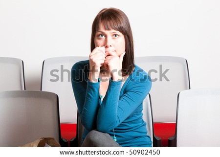 sad young woman sitting and getting emotional while watching movie, holding tissue on her face, horizontal shot
