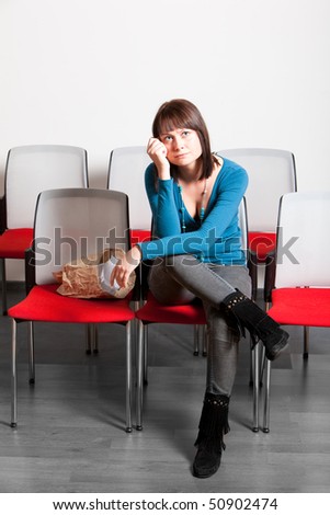 sad young woman sitting and getting emotional while watching movie, holding hand on her cheek, vertical shot