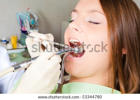 young woman patient at dentist with open mouth while drilling procedure, horizontal shot