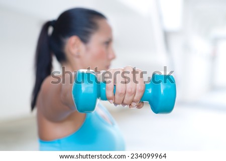 A hand holding blue dumbbell for tricep extension of sporty lady exercising