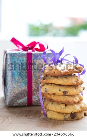 Stacks of chocolate chip cookie tied up next to a wrapped up Christmas present.