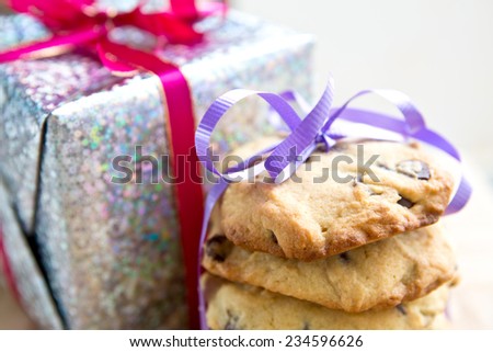 Stacks of chocolate chip cookie tied up next to a wrapped up Christmas present.