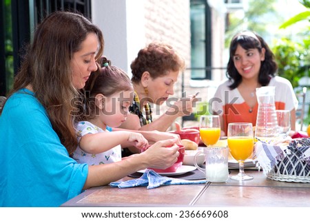 Beautiful hispanic family with a girl toddler having breakfast together on the outdoor dining showing family bonding time.