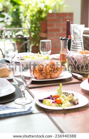 Outdoor dining meal complete with roast chicken, salad, bread rolls, wine and fruit in summer. Concept of outdoor dining.
