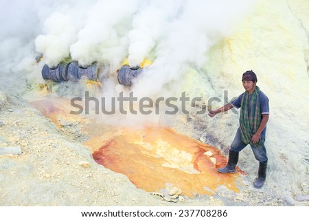 BANYUWANGI, EAST JAVA NOV 12 : Sulphur miner points to hardened sulphur from the ground to be collected and sold on Nov 12, 2012, Ijen volcano, East Java, Indonesia.