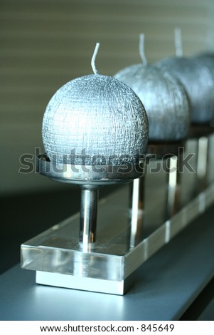 A row of unlit silver candles on a silver stand