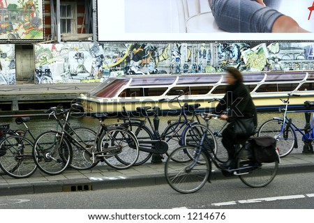 Two world:Concept of slowing down - A lady on her bike rushing past a parked boat in the canal