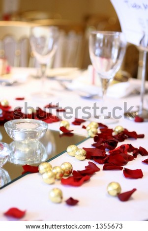 A table arrangement at a wedding reception with scattered chocolate balls, rose petals and wine glasses