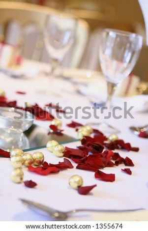 A table arrangement at a wedding reception with scattered chocolate balls, rose petals and wine glasses
