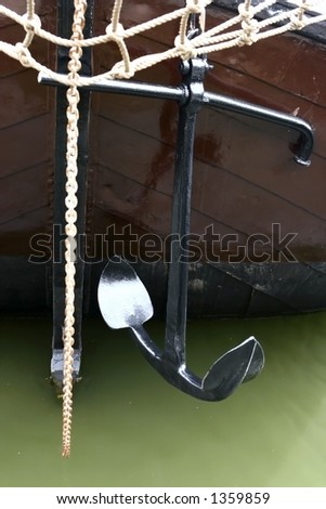 Ready to anchor. An anchor hanging  on the front of a boat, moored in the dock