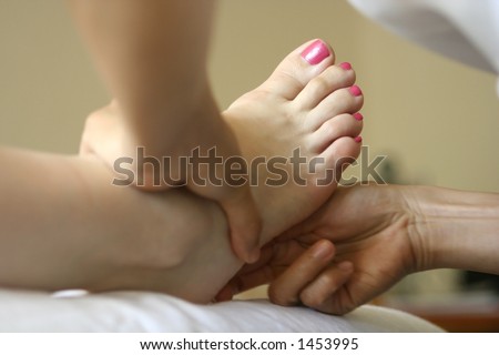 A woman receiving foot reflexology as part of a holistic massage treatment
