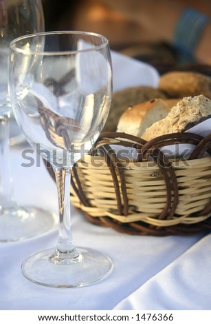 Outdoor dinner setting in the evening, consisting of an empty wine glass and a basket of bread