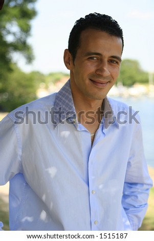 A young man in blue shirt seeking some shade under a tree