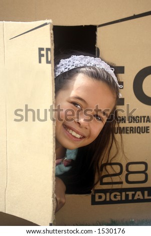 A girl plays hide and seek in a box