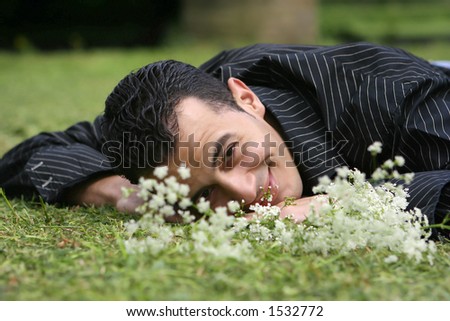 A young man laying down in field of flowers, in touch with his feelings and emotion.