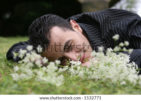 A young man laying down in field of flowers, in touch with his feelings and emotion.