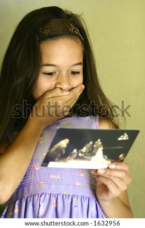 A young girl feeling surprised and glad after receiving a postcard from her friend