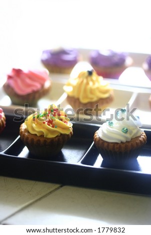 Plates of mini cupcakes with assorted decoration and colors, isolated on white