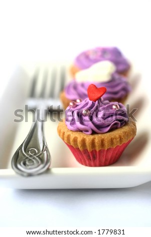 Two mini cupcakes on white plate with fork, isolated with copy space