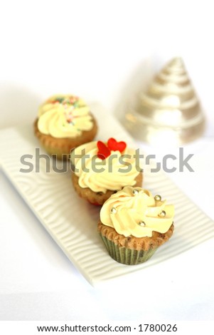 Three mini cupcakes on white plate, isolated on white with shell decoration
