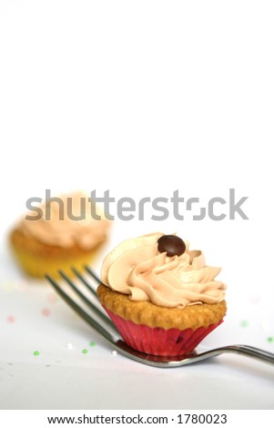 Two mini cupcakes, one on a metal fork isolated on white