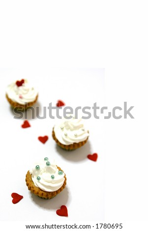 Three mini cupcakes with heartshaped decoration, isolated on white