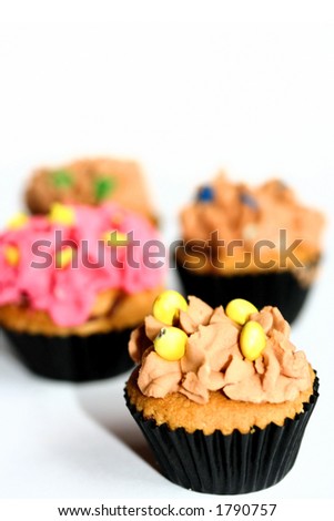 Four colorful mini cupcakes with frosting isolated on white, with copy space