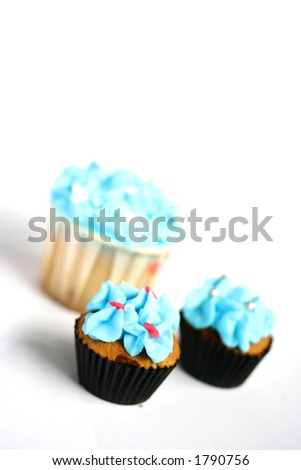 Three mini cupcakes with blue frosting, isolated on white with copy space